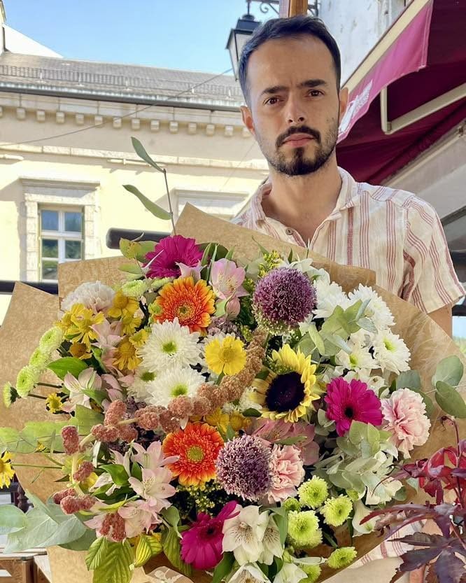 Jordan, artisan fleuriste, présentant une grande composition colorée
